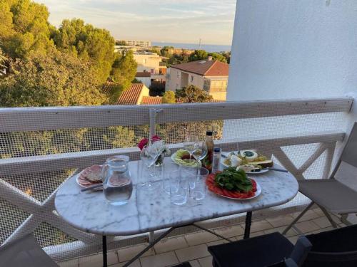 - une table avec de la nourriture et des verres à vin sur le balcon dans l'établissement Duplex à Sète - Vue sur Mer, Piscine et Parking, à Sète