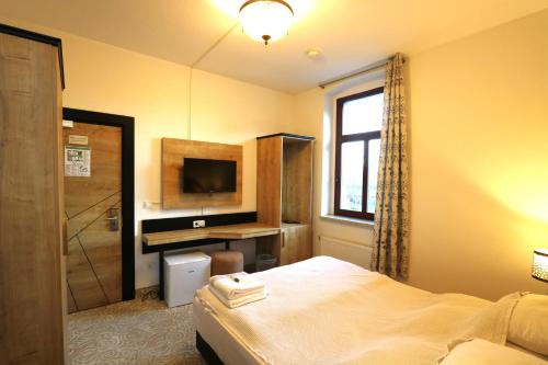 a bedroom with a bed and a desk and a television at Am Fluss Saale in Weißenfels