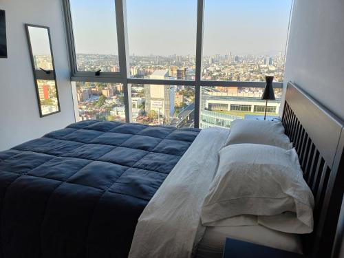 een groot bed in een kamer met een groot raam bij NSI Anseli in Mexico-Stad