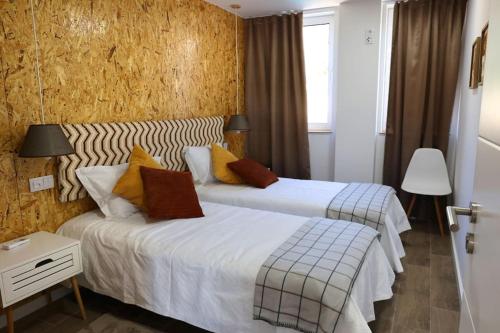 a hotel room with two beds and a window at Da Serra guesthouse in Porto de Mós