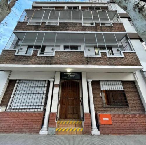 a tall brick building with a door and windows at Hotel Yerbal in Buenos Aires