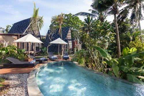 a swimming pool in front of a villa at TUJUH Angel by GenuineHost in Ubud