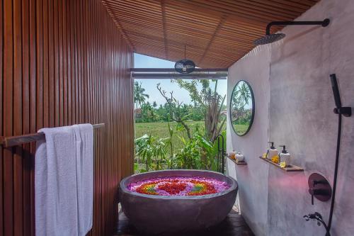 a bathroom with a large tub filled with flowers at IPIAN Angel by Pramana Villas in Ubud