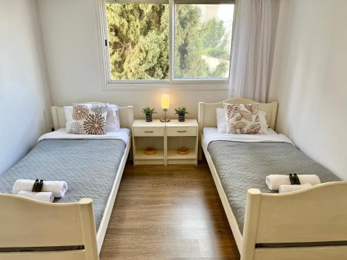 two beds in a room with a window at Shiny Blue Apartment in Limassol