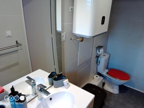 baño con lavabo y aseo con asiento rojo en Le Long island en Rivière-Pilote