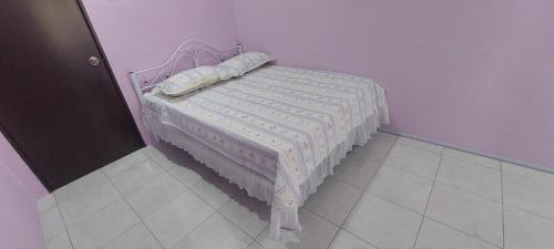 een klein bed in een kamer met een paarse muur bij TIQ Homestay KLIA in Sepang