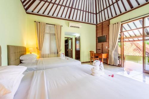 a bedroom with two white beds and a large window at Taman Surgawi Resort & Spa in Jasri