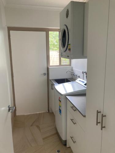 een keuken met witte kasten en een deur met een raam bij Beaches 9 in Merimbula