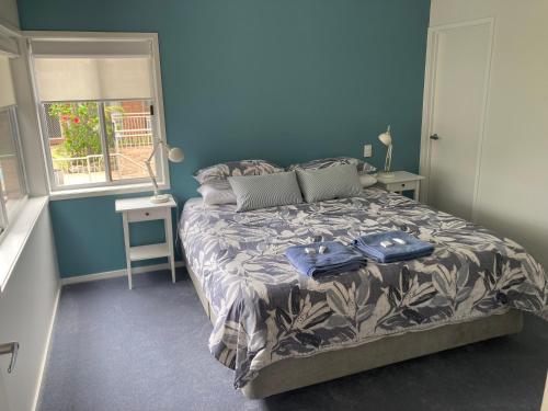 Schlafzimmer mit einem Bett mit blauen Wänden und einem Fenster in der Unterkunft Beaches 9 in Merimbula