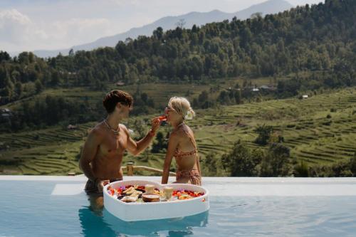 a man and woman in the water with a tub of food at Maha Hills Resort by Mahaprana Experience in Lovina