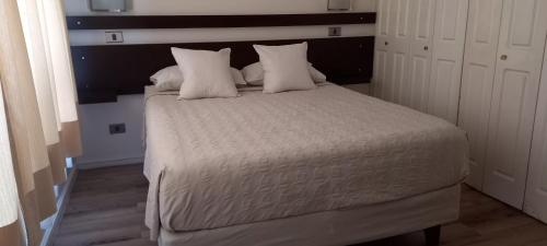 a bed with white sheets and pillows in a room at Apart Hotel Inga Providencia in Santiago