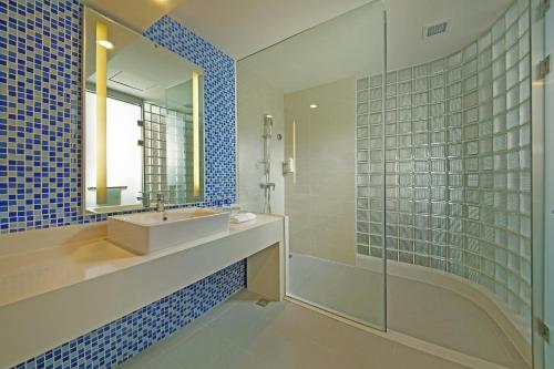 uma casa de banho com um lavatório, um espelho e um chuveiro em Holiday Inn Express Tangshan Downtown, an IHG Hotel em Tangshan