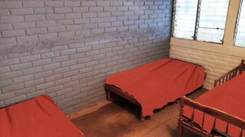 a room with two beds and a brick wall at Rancho santa cecilia in Sonsonate
