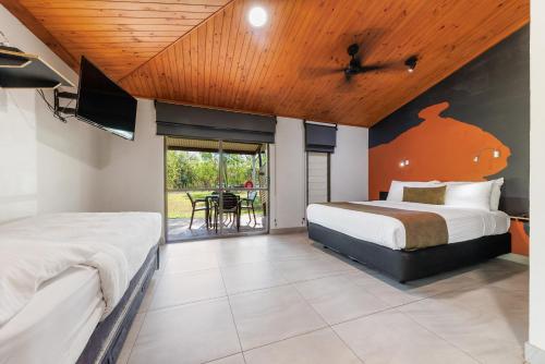 a bedroom with a bed and a tv and a patio at Cooinda Lodge Kakadu in Jabiru