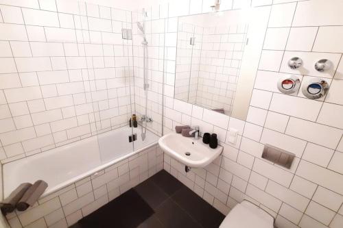 a white tiled bathroom with a sink and a toilet at Modern building with vertical garden & 2 bedrooms in Berlin