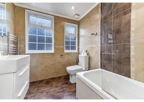 a bathroom with a toilet and a sink and a tub at Homey and Pleasant 3BD in London
