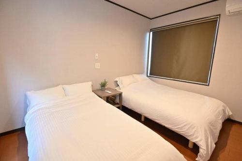 two beds in a room with a large window at 別邸 安 in Beppu
