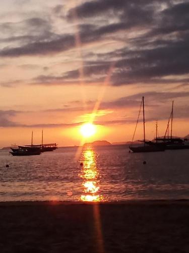 a sunset over the ocean with boats in the water at Casa com Praia no quintal in Angra dos Reis