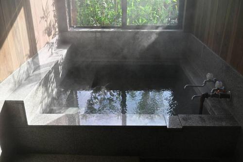 a bath tub with a water fountain in a room at 別邸 安 in Beppu