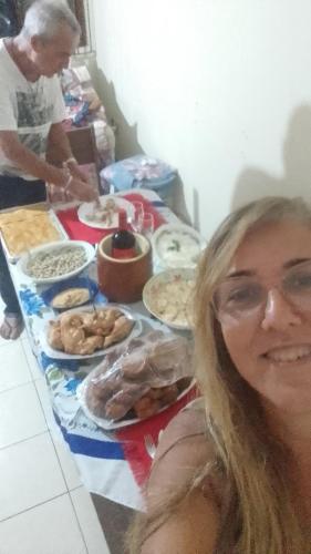 a woman sitting in front of a table of food at Hospedaria Meu Lar in Rio das Ostras