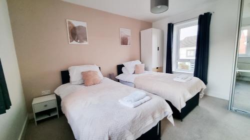 two beds in a room with a window at Family & Business Stays In RG2 - Sleeps Up to 12! in Reading