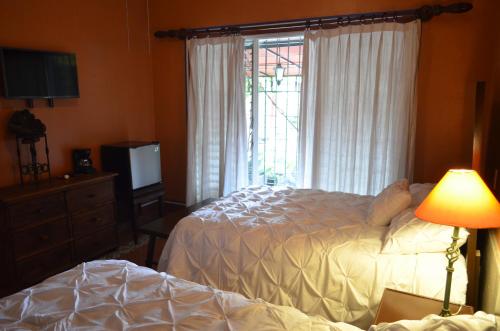 a bedroom with a bed and a television and a window at Hotel Art Gallery Casona de los Milagros in Colima