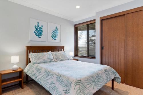 a bedroom with a bed and a wooden door at Daybreak by Experience Jervis Bay in Vincentia