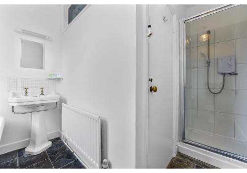 a white bathroom with a sink and a shower at Handsome Family Home Peaceful, Next to Park in London