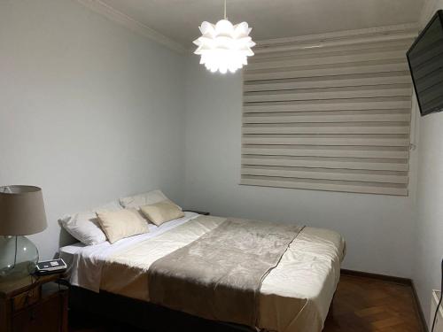 ein weißes Schlafzimmer mit einem Bett und einem Kronleuchter in der Unterkunft BBCasita Las Condes in Santiago