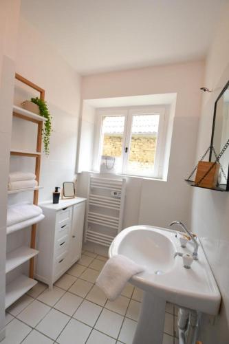 a white bathroom with a sink and a window at Chez maria in Celles-sur-Ource