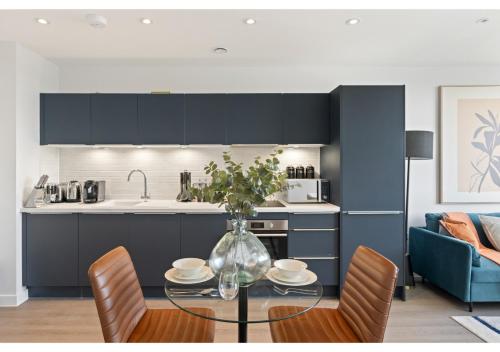 a kitchen and dining room with a glass table and chairs at Beckenham Beauty: Modern 1-Bedroom Abode in Beckenham