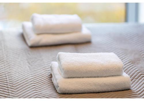 three towels sitting on top of a bed at Beckenham Beauty: Modern 1-Bedroom Abode in Beckenham