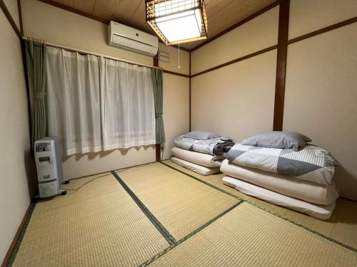 two beds in a room with a window at Nagayama Home in Asahikawa