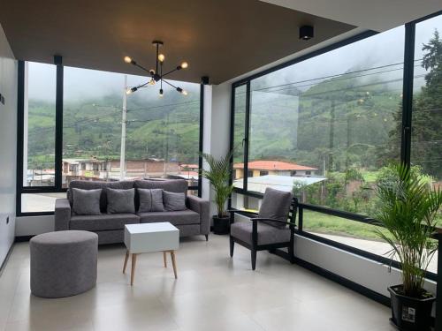 ein Wohnzimmer mit einem Sofa und Stühlen sowie großen Fenstern in der Unterkunft LAS TOLAS HOTEL-RESTAURANTE in Pallatanga