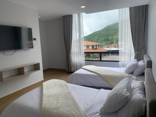 Habitación de hotel con 2 camas y TV de pantalla plana. en LAS TOLAS HOTEL-RESTAURANTE, en Pallatanga