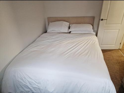 a white bed with two pillows in a bedroom at Well Furnished 3 Bedroom House in a cosy estate in Bolton in Bolton