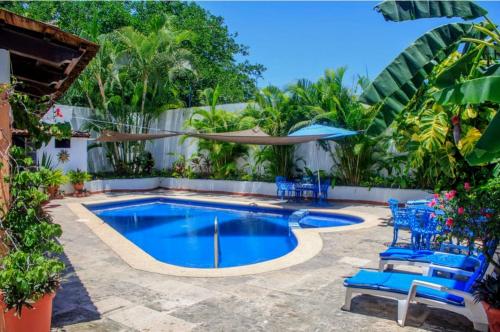 a swimming pool with blue chairs and an umbrella at Casa las Flores in Puerto Vallarta