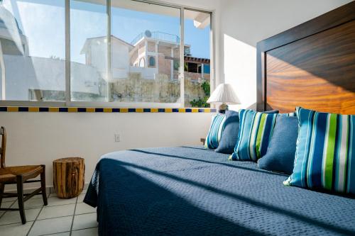 Schlafzimmer mit einem blauen Bett und einem großen Fenster in der Unterkunft Hacienda Lord Twigg - Hotel & Suites in Puerto Vallarta