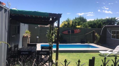 un patio trasero con una piscina con una tabla de surf sobre una valla en Casa container con pileta a 4 cuadras de la playa en Quequén