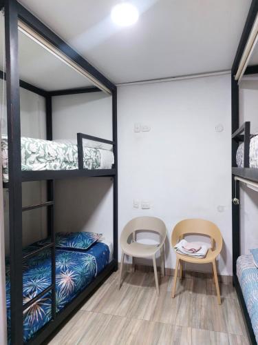 a room with bunk beds and a table and a chair at Hotel Casa Huesped Kiwi in Bogotá