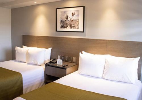 a hotel room with two beds with white pillows at Hotel Calafia in Mexicali