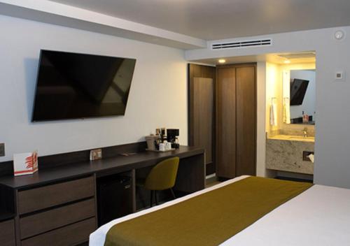 a hotel room with a bed and a desk and a sink at Hotel Calafia in Mexicali