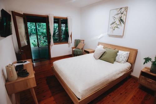 a bedroom with a bed with white sheets and green pillows at Paperbark Retreat in Cooktown