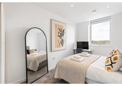 Dormitorio blanco con espejo y cama en Sophisticated Living: 1-BR Flat in Beckenham en Beckenham