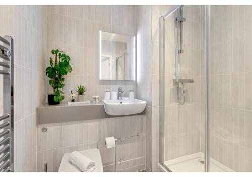 ein weißes Bad mit einem Waschbecken und einer Dusche in der Unterkunft Sophisticated Living: 1-BR Flat in Beckenham in Beckenham