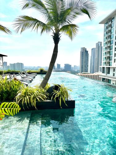 a swimming pool with a palm tree and buildings at Riviera Wongamat in North Pattaya