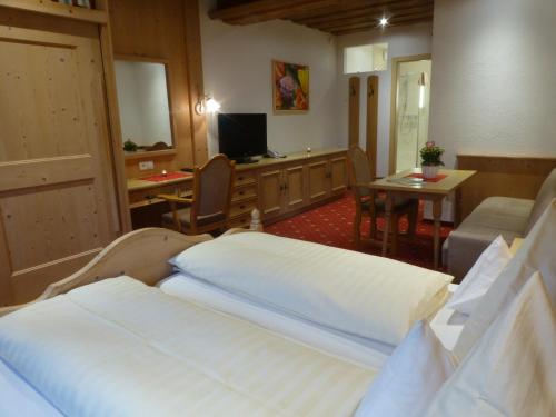 a hotel room with two beds and a desk at Alpenhof Wohlfühlpension in Obsteig