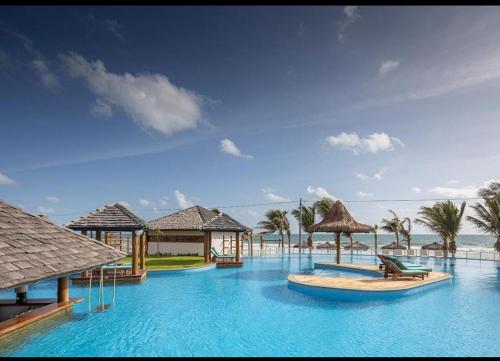 un resort con piscina con sedie e palme di The Coral Resort - Loft na Praia de Flecheiras a Trairi