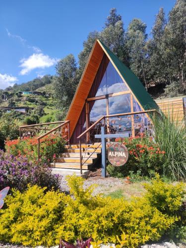 a cabin with a green roof in a garden with flowers at Aldea Fuquenense in Fúquene
