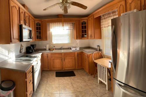 eine Küche mit Holzschränken und einem Kühlschrank aus Edelstahl in der Unterkunft Cozy Brick House Mins to Hospital in Goldsboro